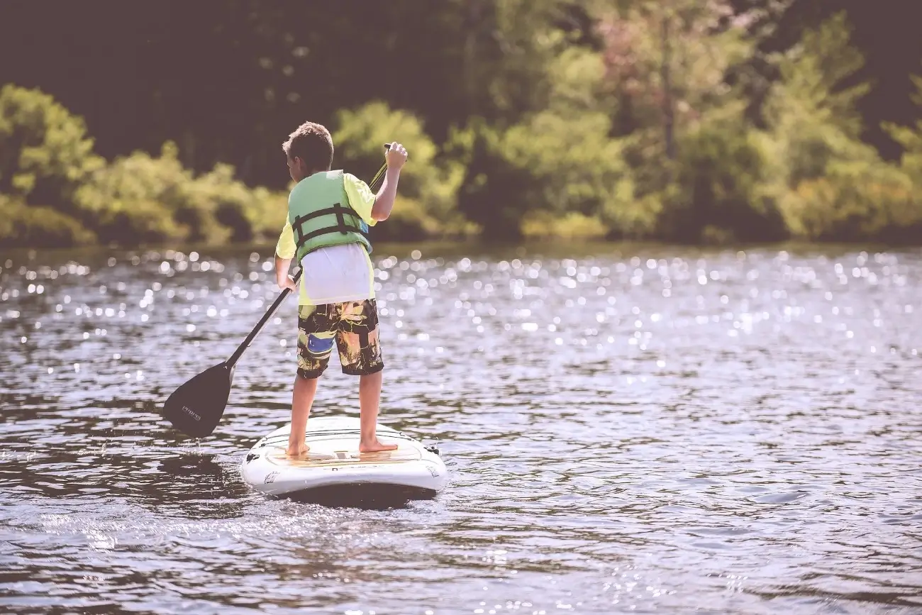niño haciendo paddle surf en el agua