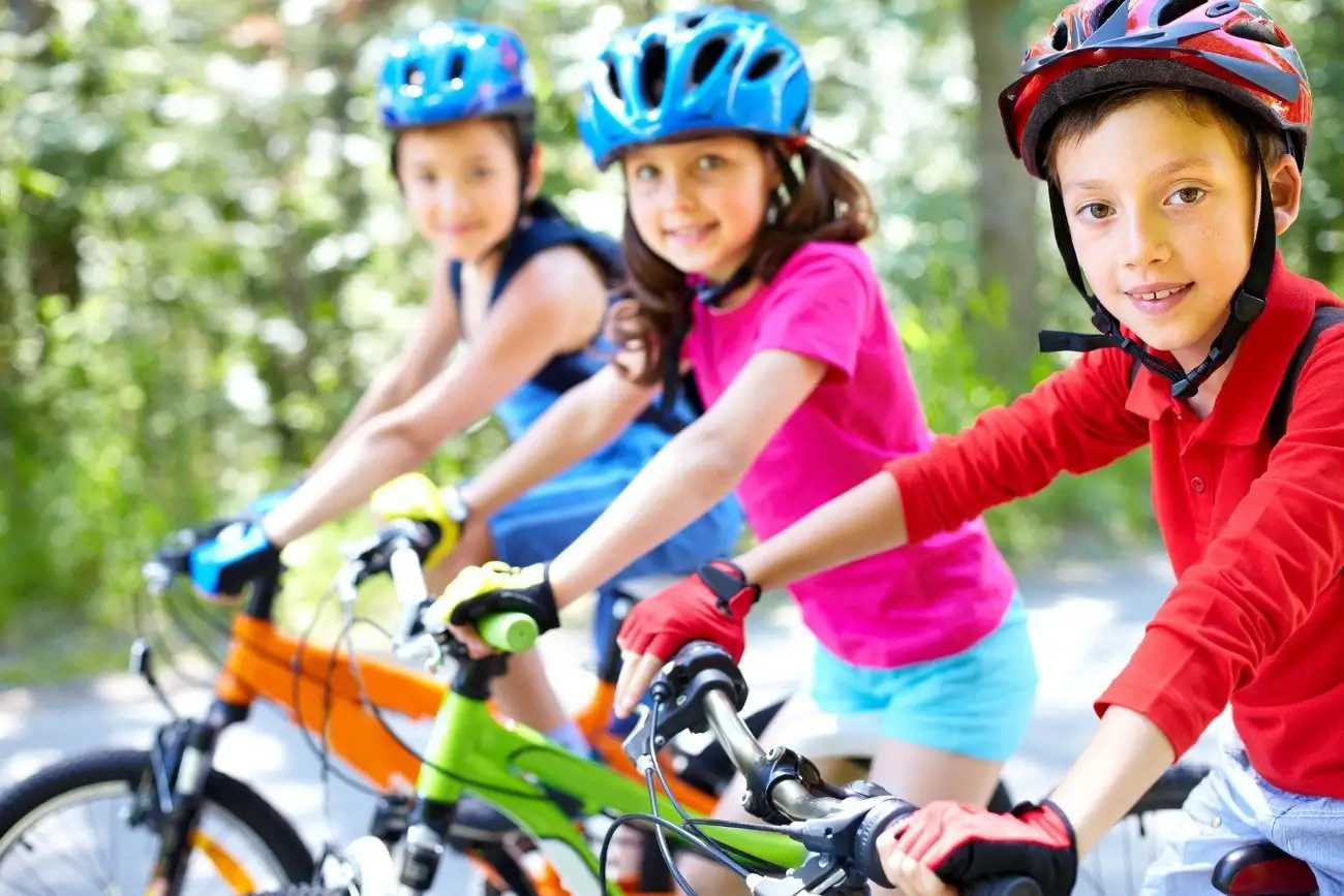 niños en bicicleta y con casco mirando a cámara