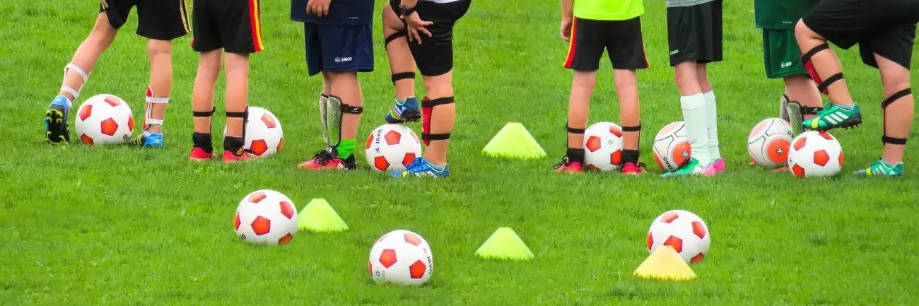 balones y pies de niños entrenando y haciendo fútbol