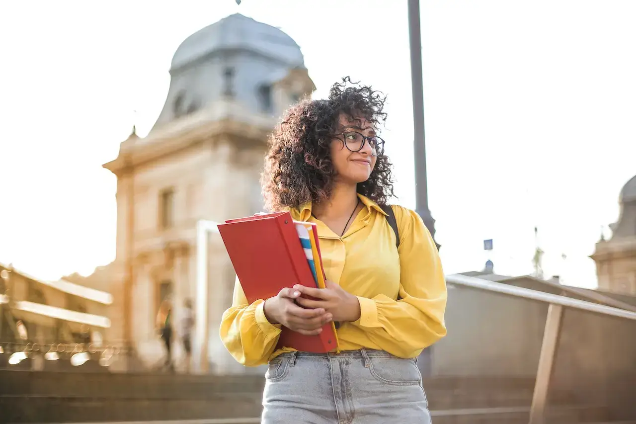 chica de color con una carpeta de estudiante en el brazo